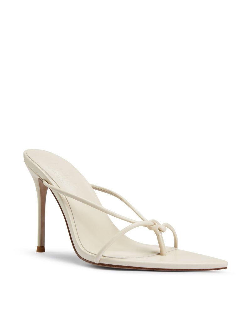 Akira Slipper in Cream – front three-quarter view showing knotted toe loop, crossed straps and pointed toe